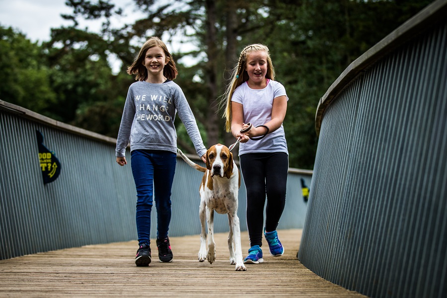 Girls with a dog walking over a bridge at Westonbirt